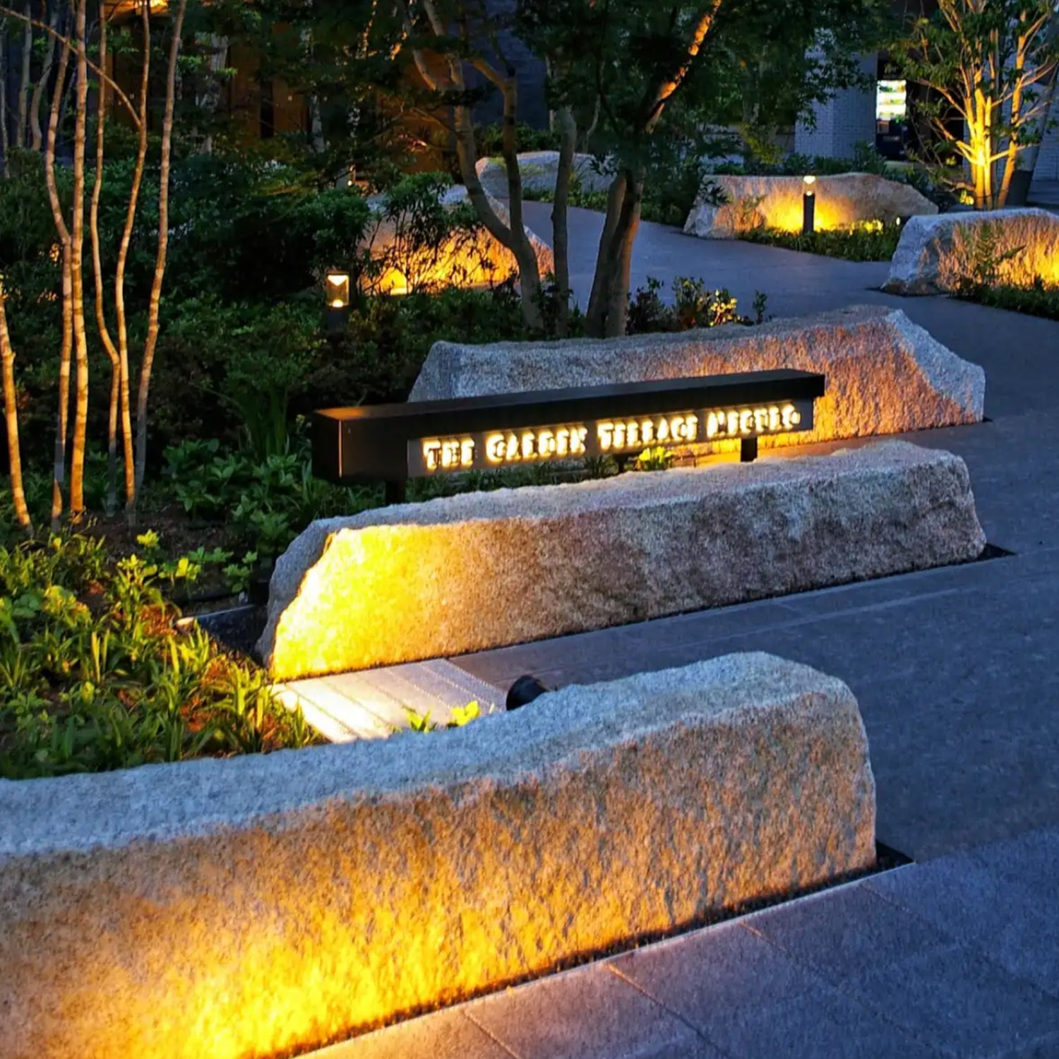 LED landscape lighting illuminating a outdoor garden with stone benches at The Garden Terrace MIPE