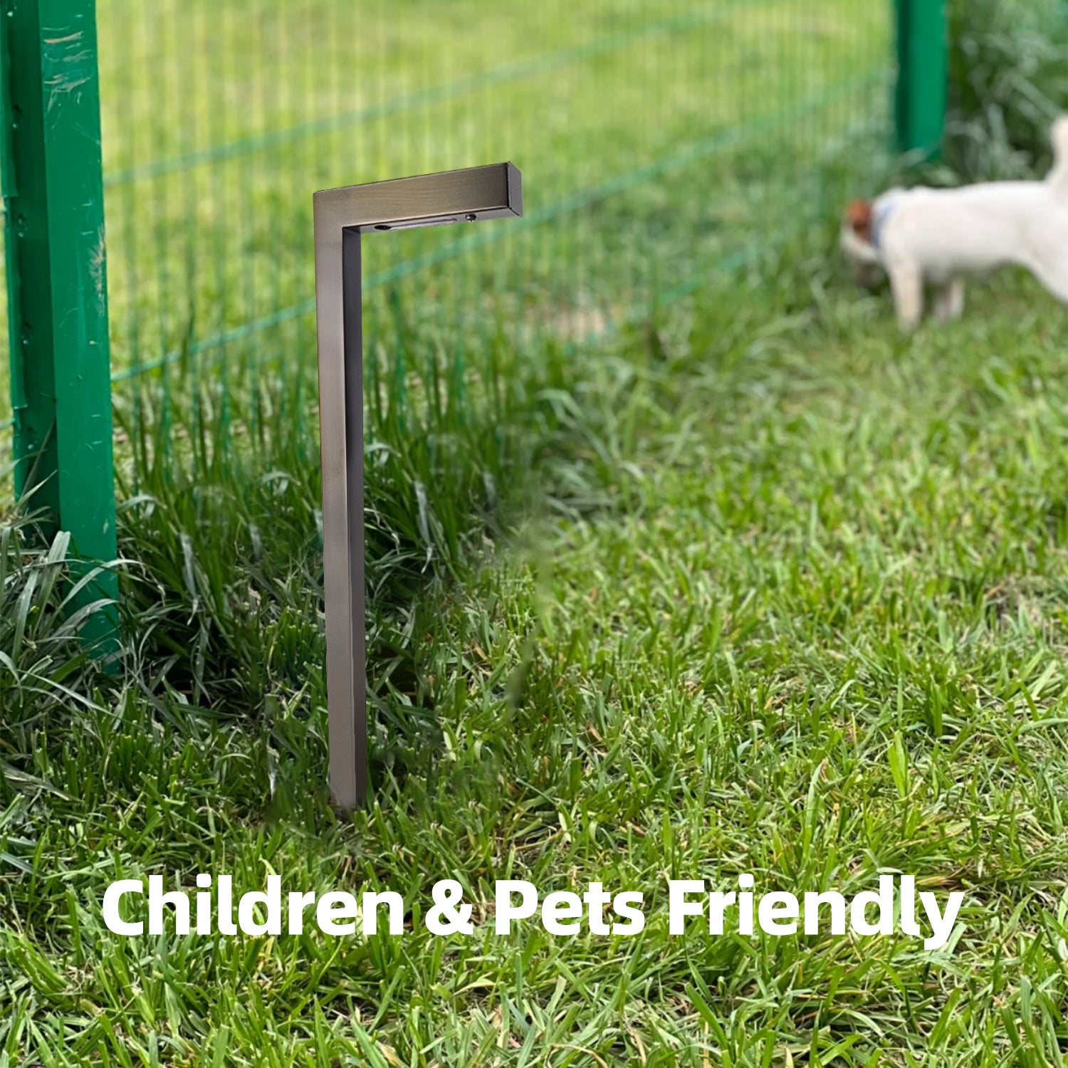 L-shaped brass outdoor path light installed on grassy area near green fence, with text 'Children & Pets Friendly' indicating safe for children and pets, dog in the background.