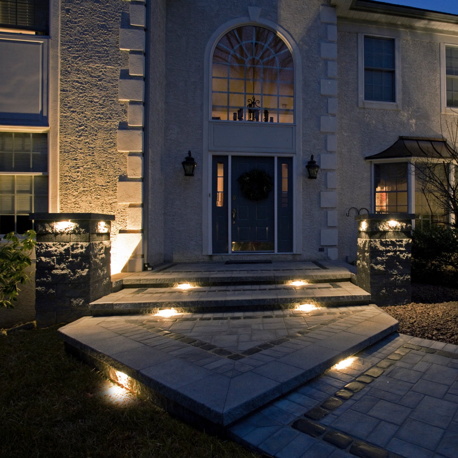 Front entrance of a house illuminated with LED hardscape lights on the steps, creating a warm and welcoming ambiance at night