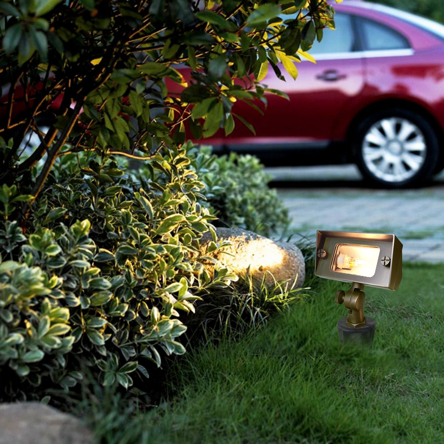 Brass outdoor rectangular flood light illuminating garden plants with a red car in the background. Ideal for highlighting landscape features.